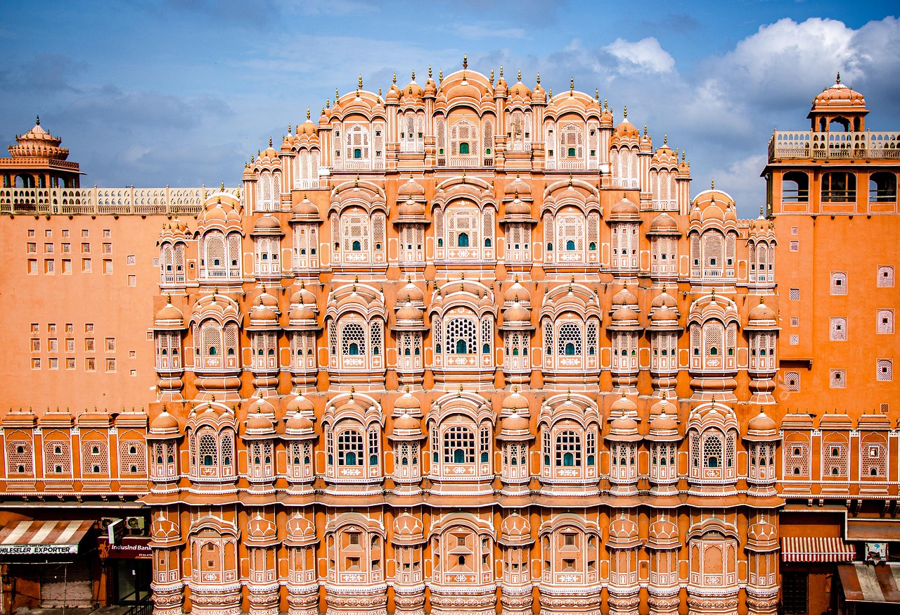 The ornate facade of the Hawa Mahal palace in Jaipur, India, featuring intricate latticework and numerous windows.
