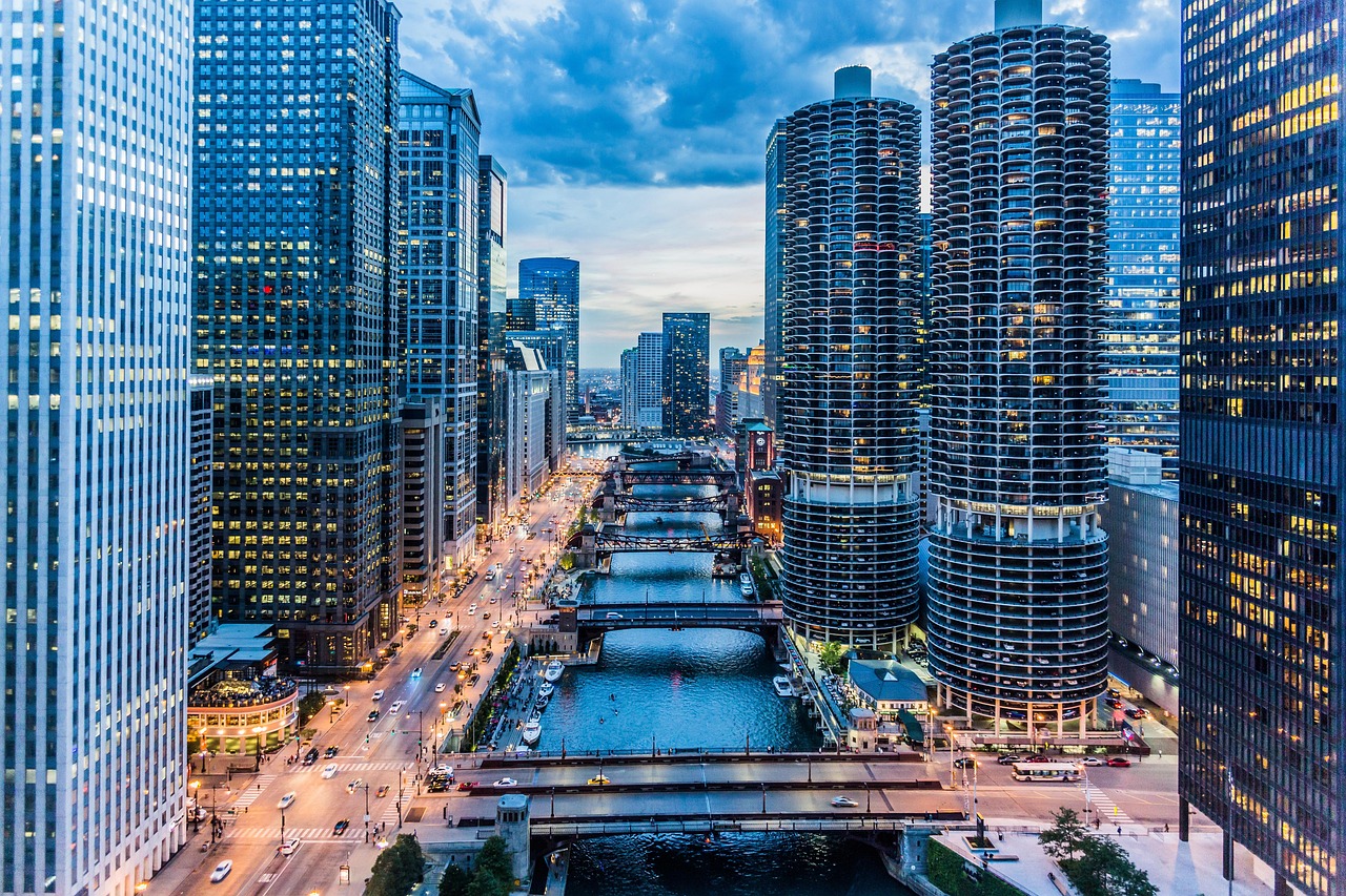 Aerial view of a cityscape with tall buildings, a river, and bridges at dusk.