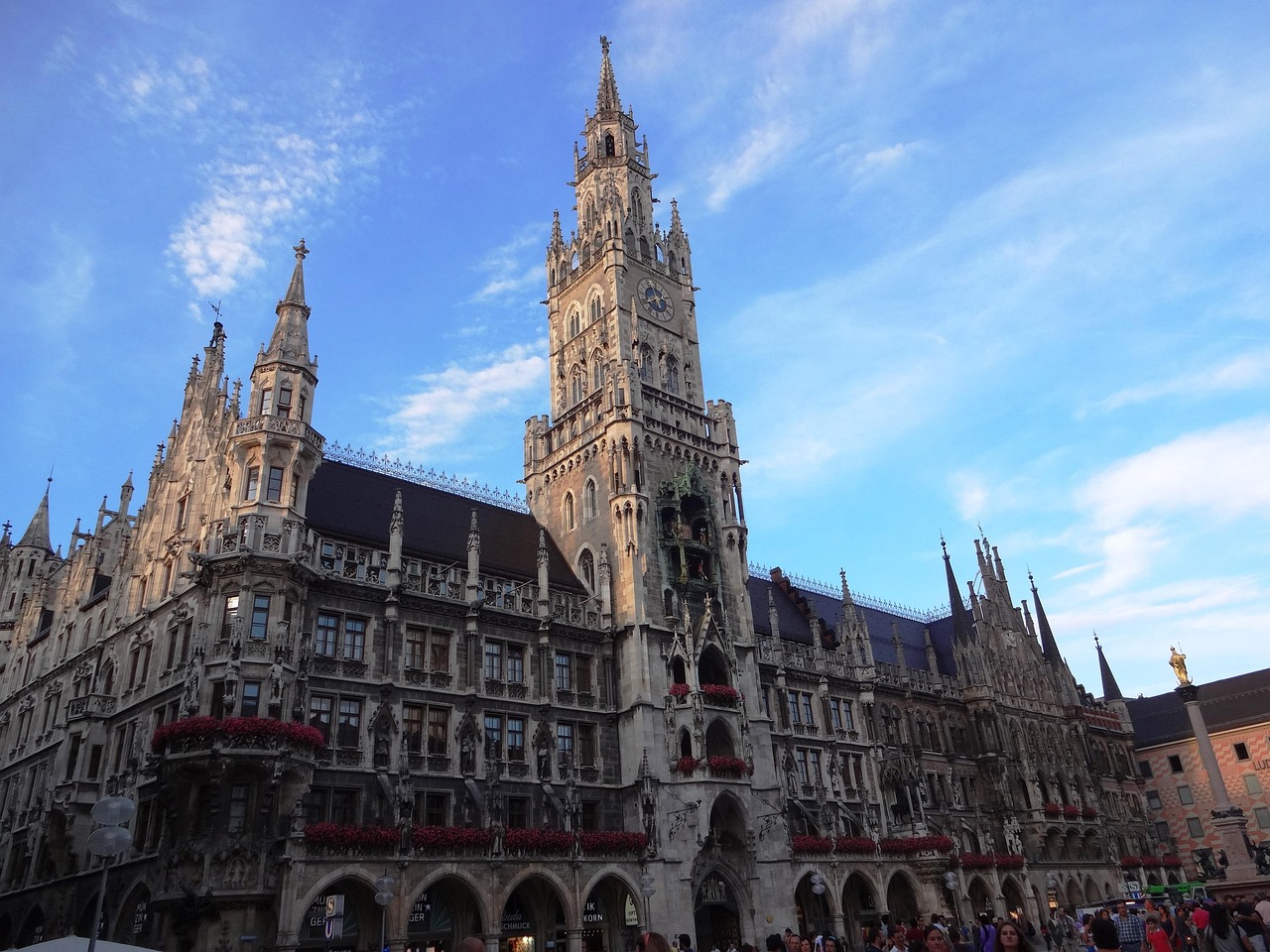 A grand historic building with tall spires and intricate details, with people gathered in front of it.