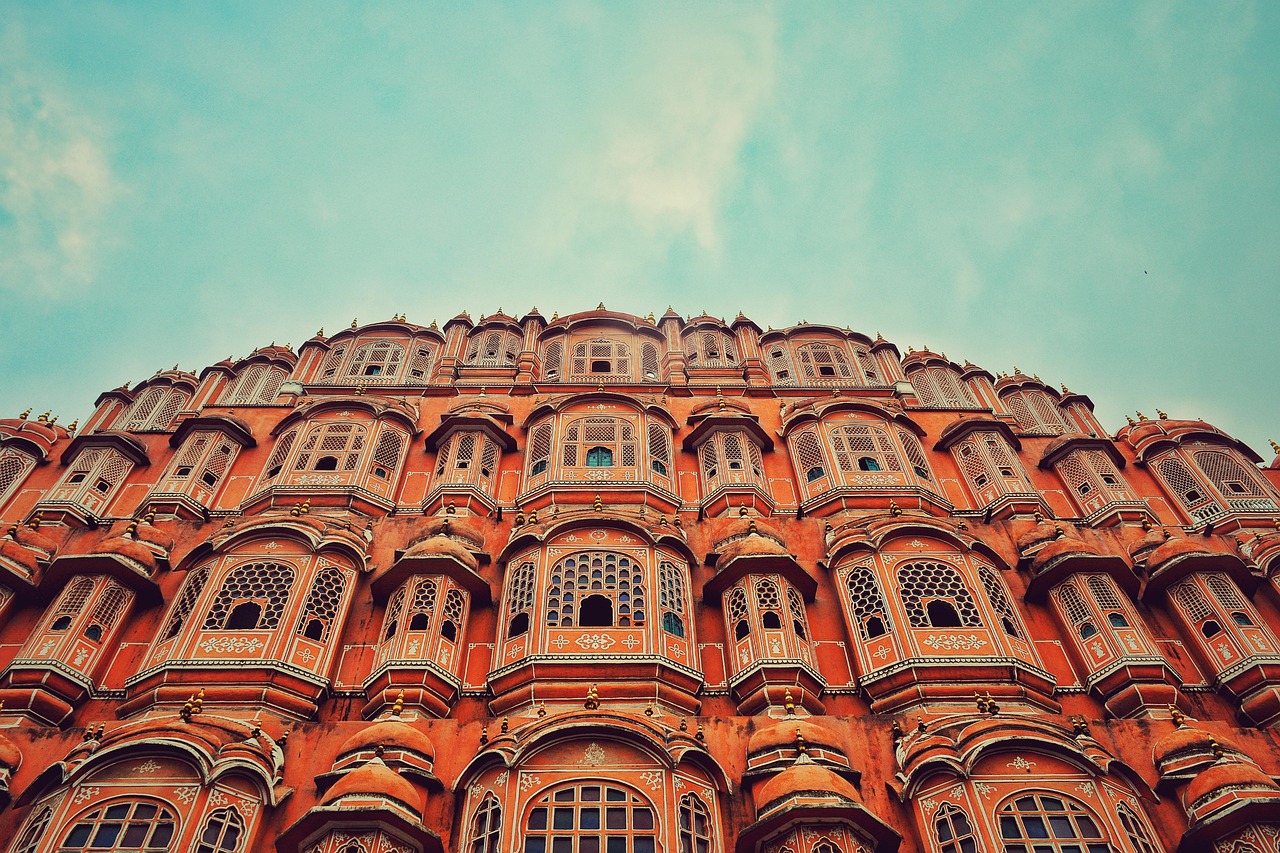 A detailed view of the Hawa Mahal palace in Jaipur, India, showcasing its intricate red and pink sandstone latticework and windows.
