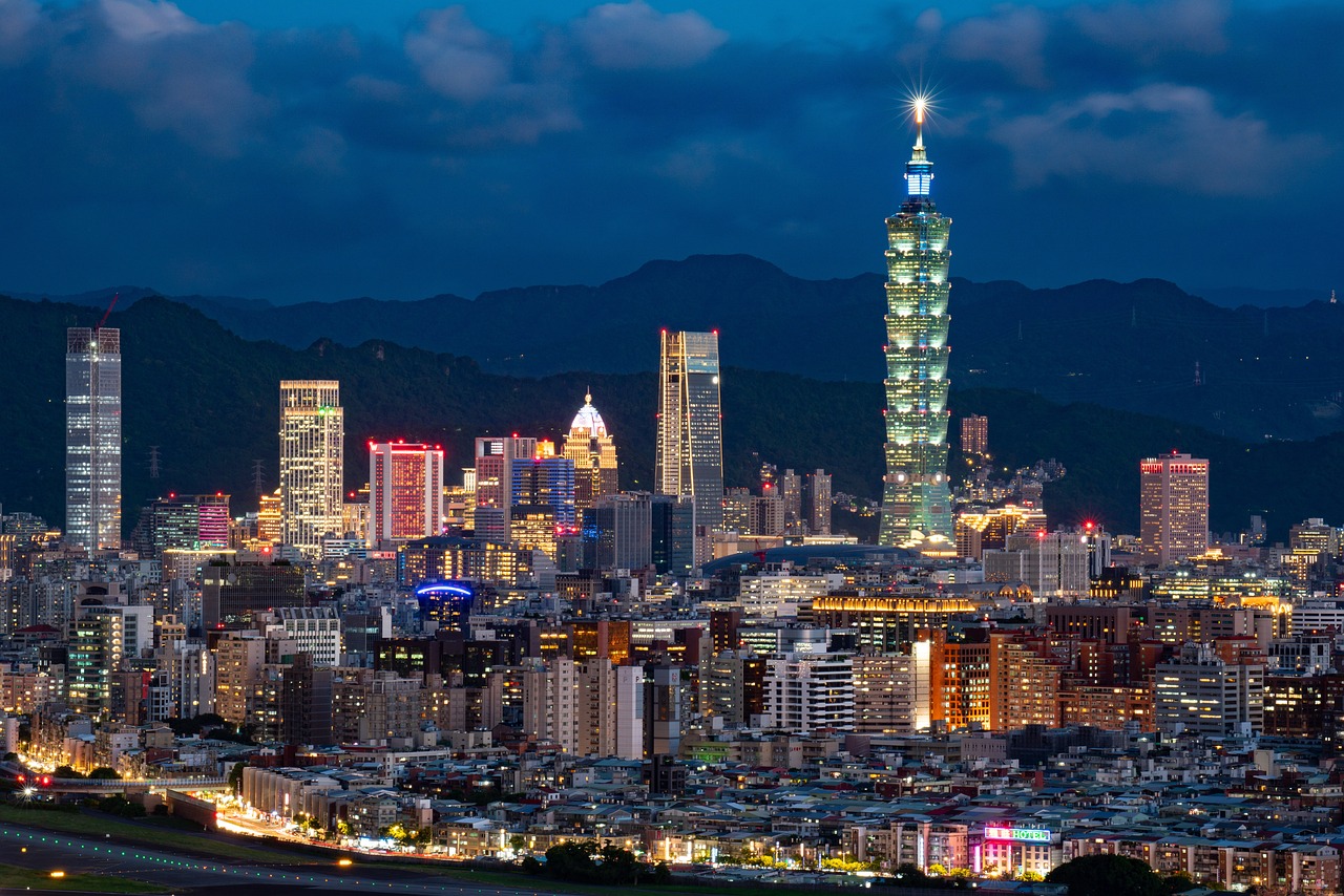 Nighttime cityscape of Taipei with the Taipei 101 skyscraper prominently lit.