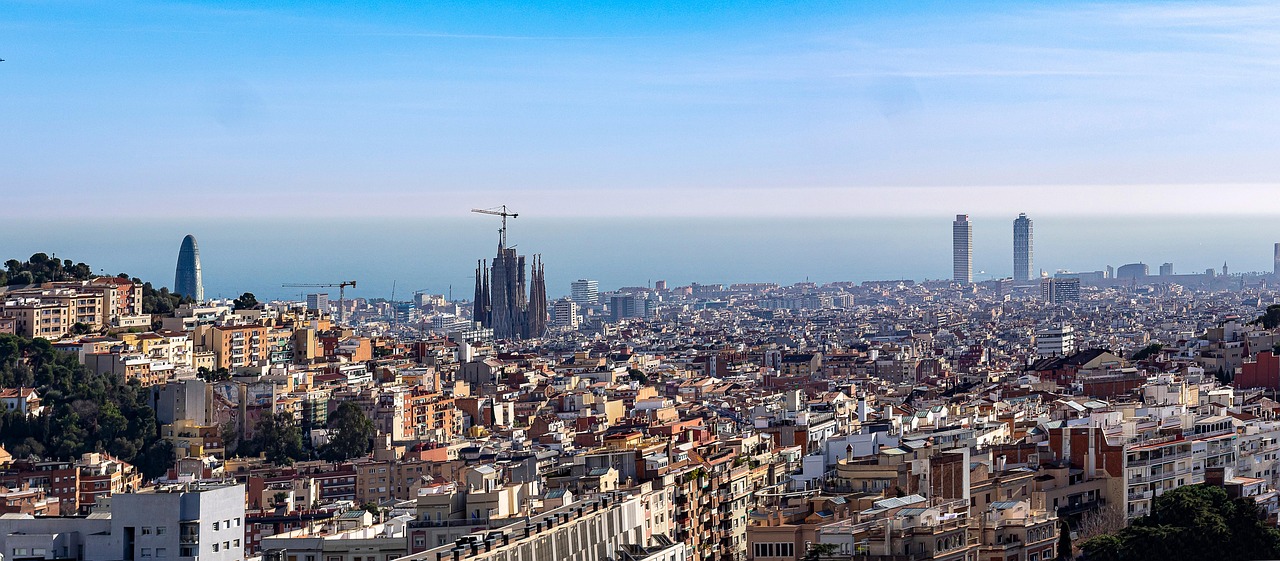 A panoramic view of a city with distinctive architecture and skyline, including the Sagrada Familia.