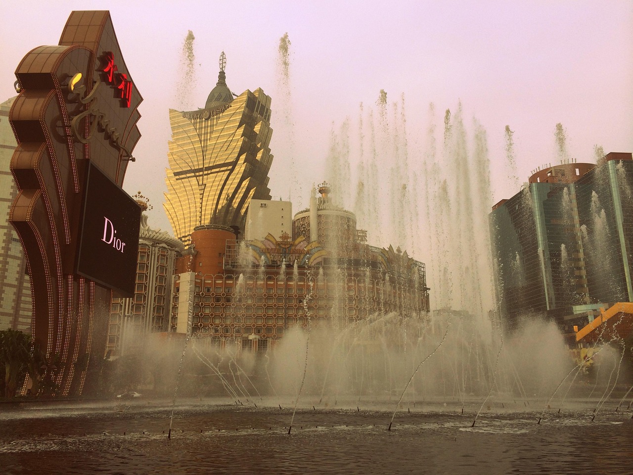 A cityscape with a large fountain in the foreground and modern buildings in the background, including a Dior store.