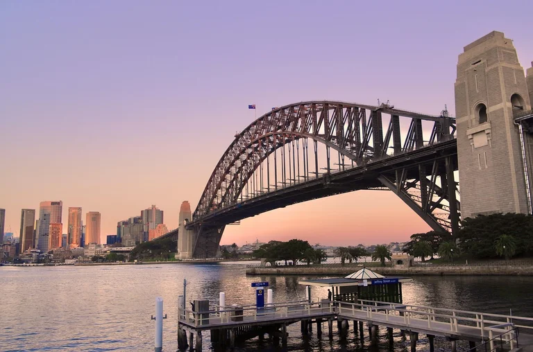 A view of the Sydney Harbour Bridge at sunset with the city skyline in the background.