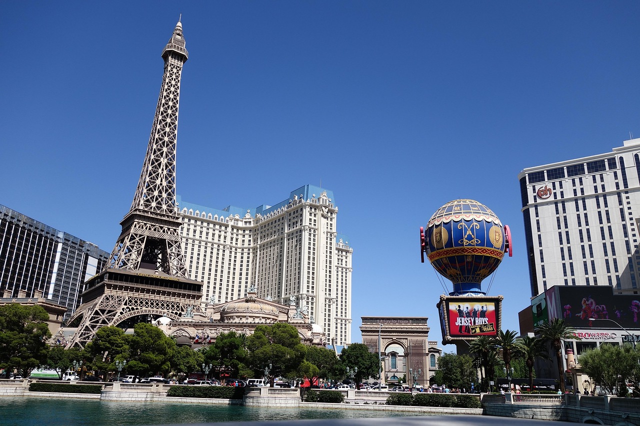 A replica of the Eiffel Tower and an arc de triomphe in front of a large hotel with a hot air balloon advertisement in Las Vegas.