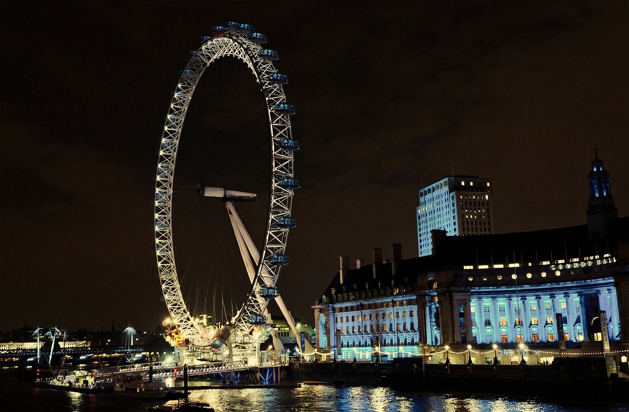 The London Eye illuminated at night with the County Hall building in the background.