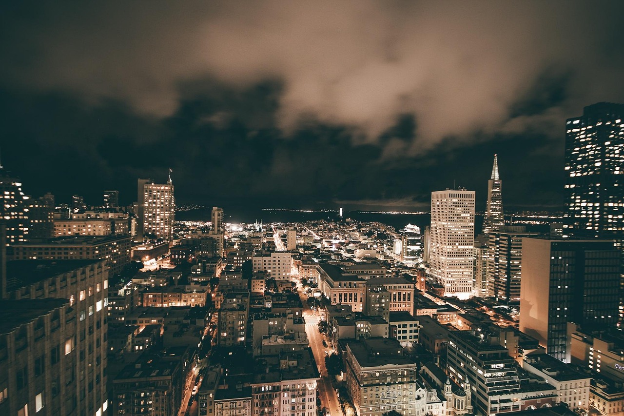 Nighttime cityscape of San Francisco with illuminated skyscrapers and the Transamerica Pyramid visible.