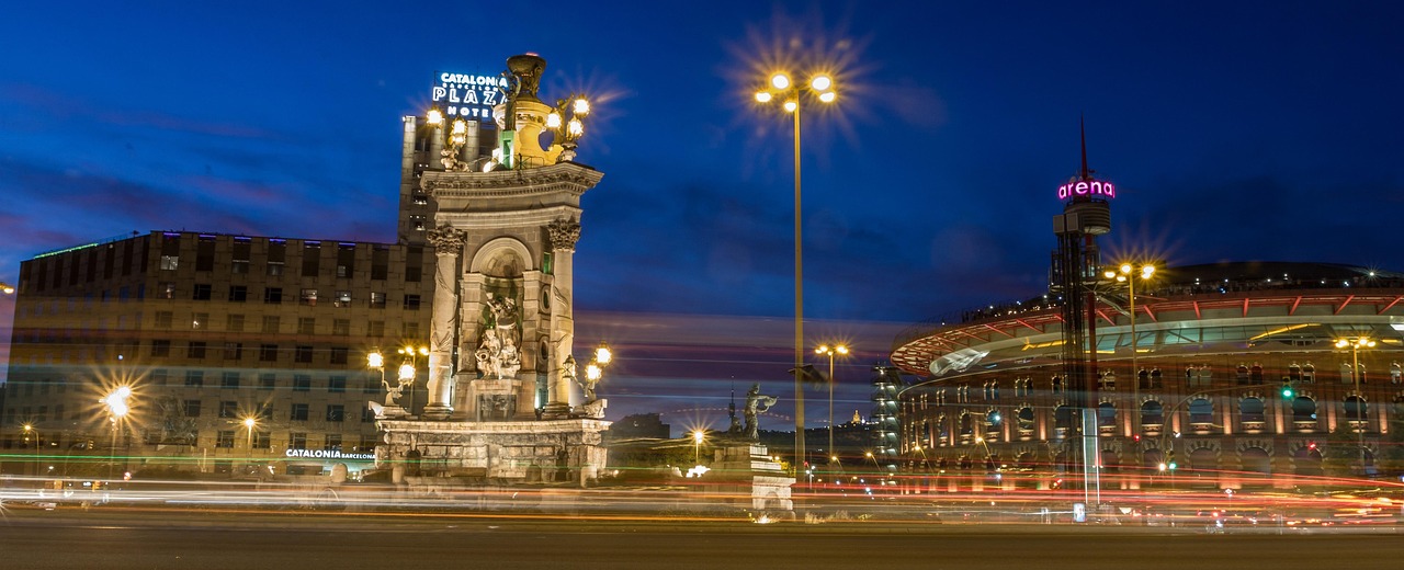 Night view of a city with a prominent monument and a large stadium in the background.