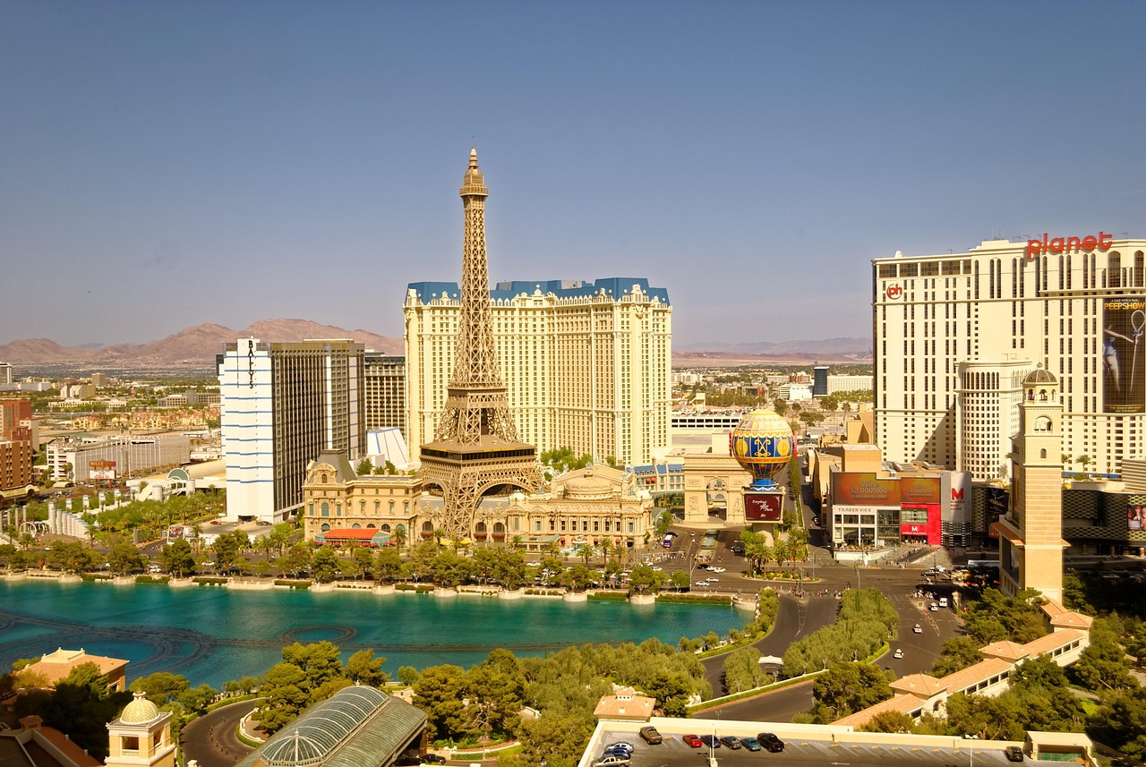 Aerial view of a city with a prominent Eiffel Tower replica, hotels, and a large pool.