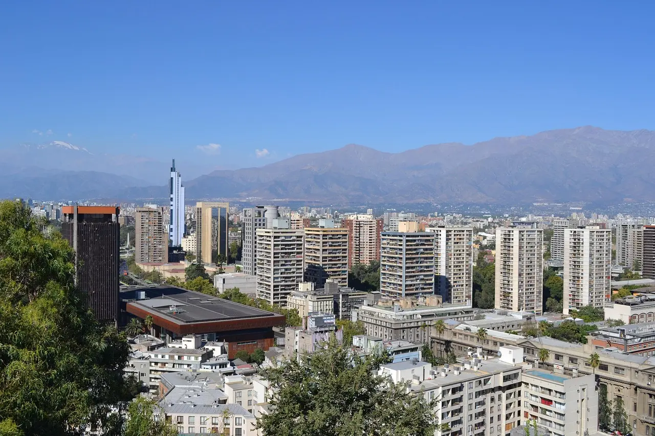 A cityscape view of Santiago, Chile, with tall buildings and mountains in the background.
