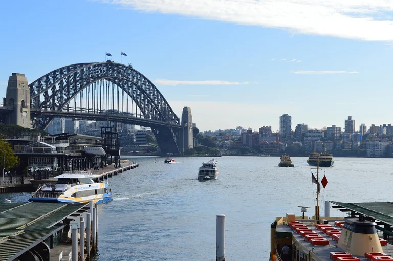 A view of the Sydney Harbour Bridge with boats on the water and the city skyline in the background.
